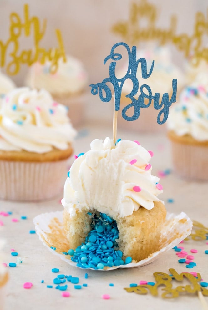 Gender reveal cupcake cut in half with blue sprinkles pouring out of center