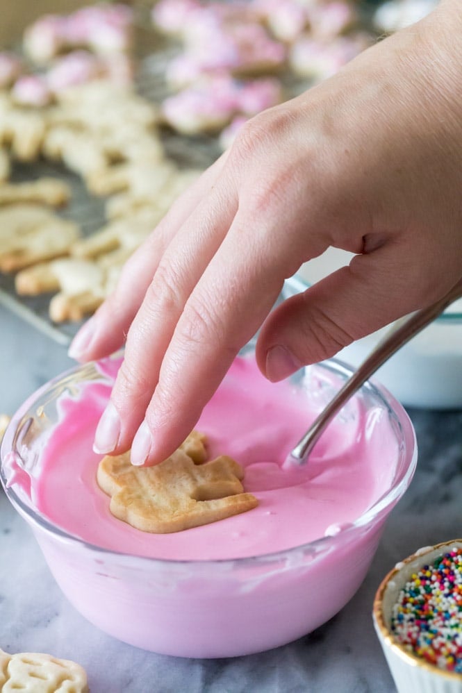Dipping animal cookies in pink frosting