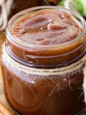 Rich brown apple butter recipe in a glass jar tied with twine