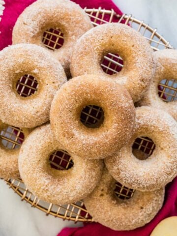 Top-down view of nine apple cider donuts on cooling rack