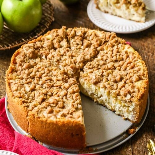 Whole apple pie cheesecake that's been cut into slices with one slice missing.