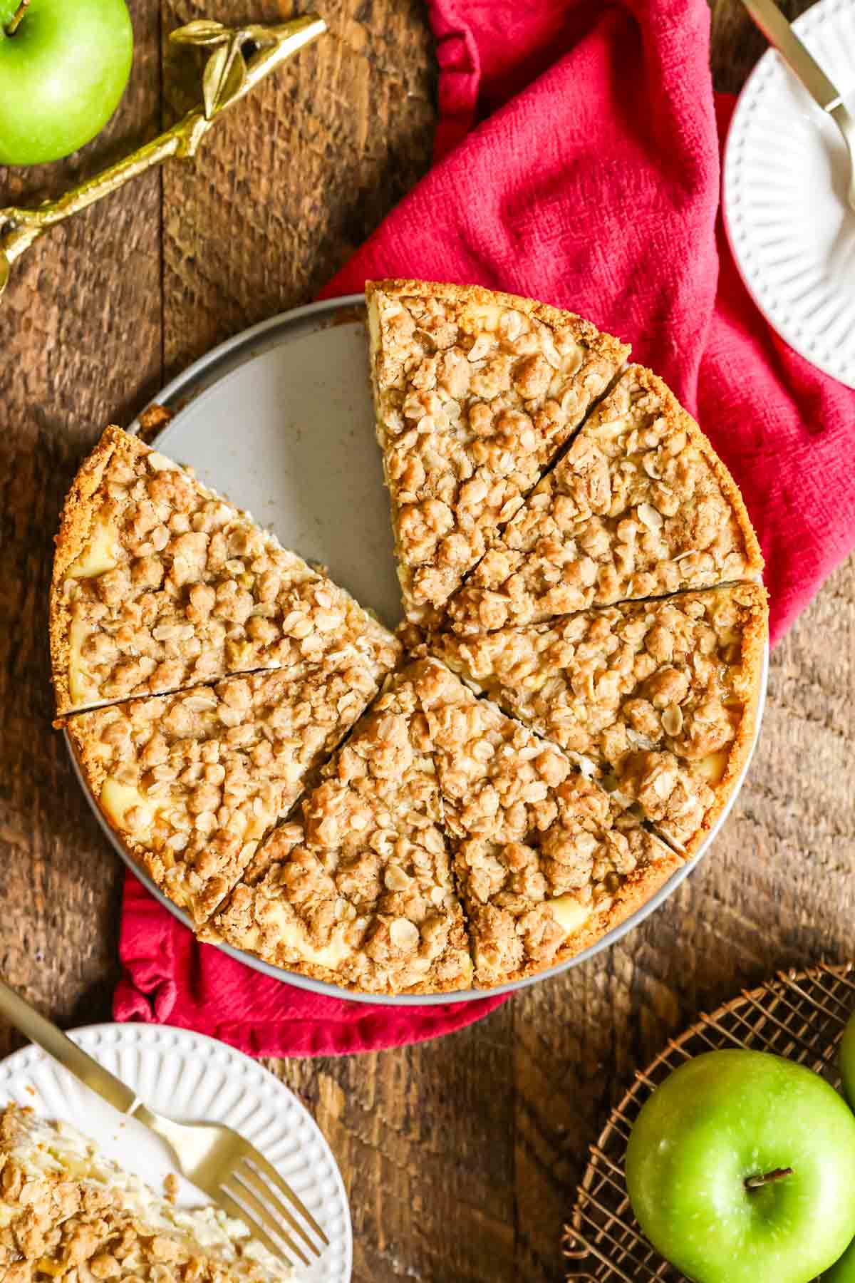 Overhead view of a streusel topped cheesecake surrounded by granny smith apples.