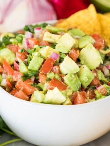 avocado salsa in white bowl with corn chips