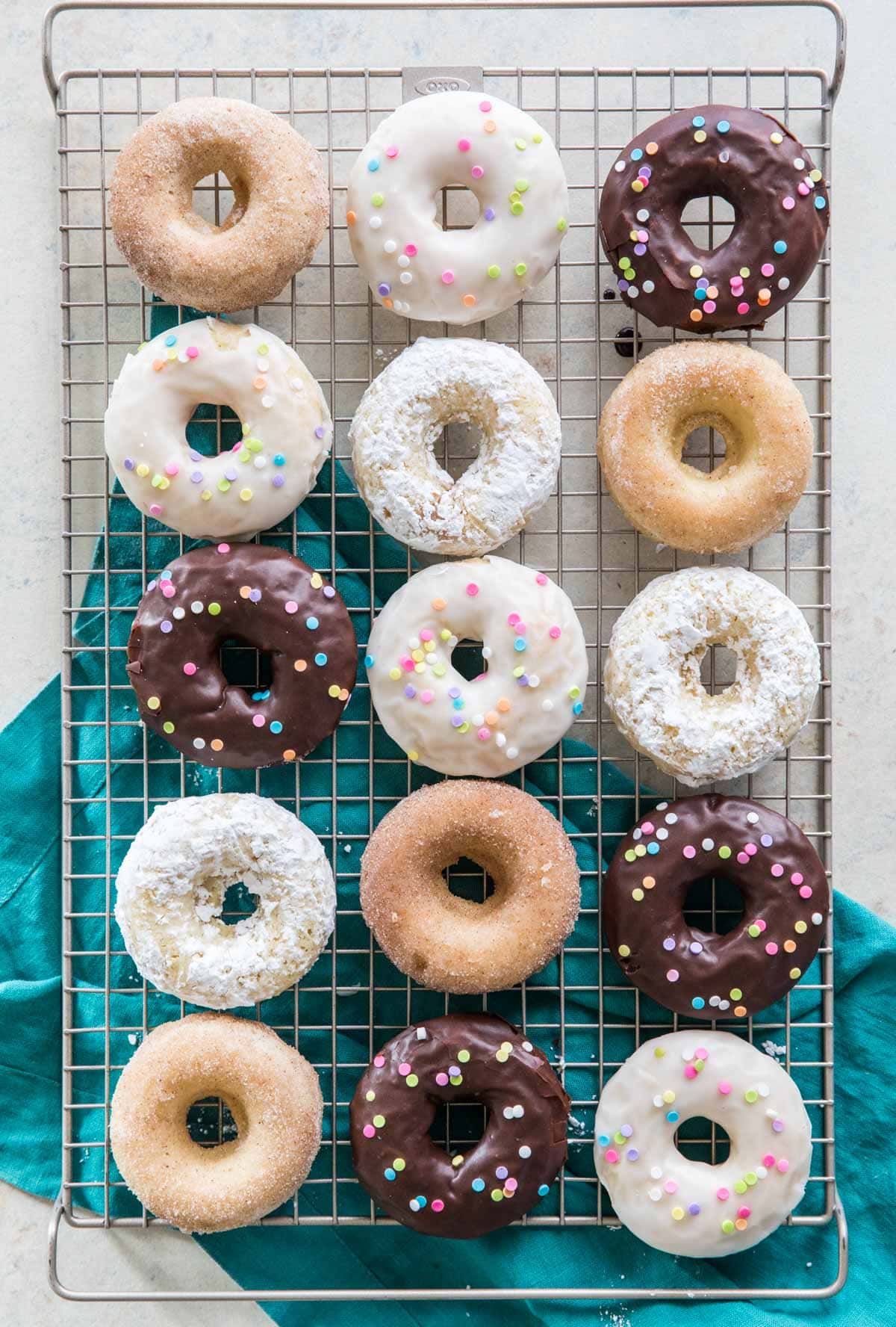 overhead of baked donuts with different toppings (chocolate frosting, cinnamon sugar, white frosting)