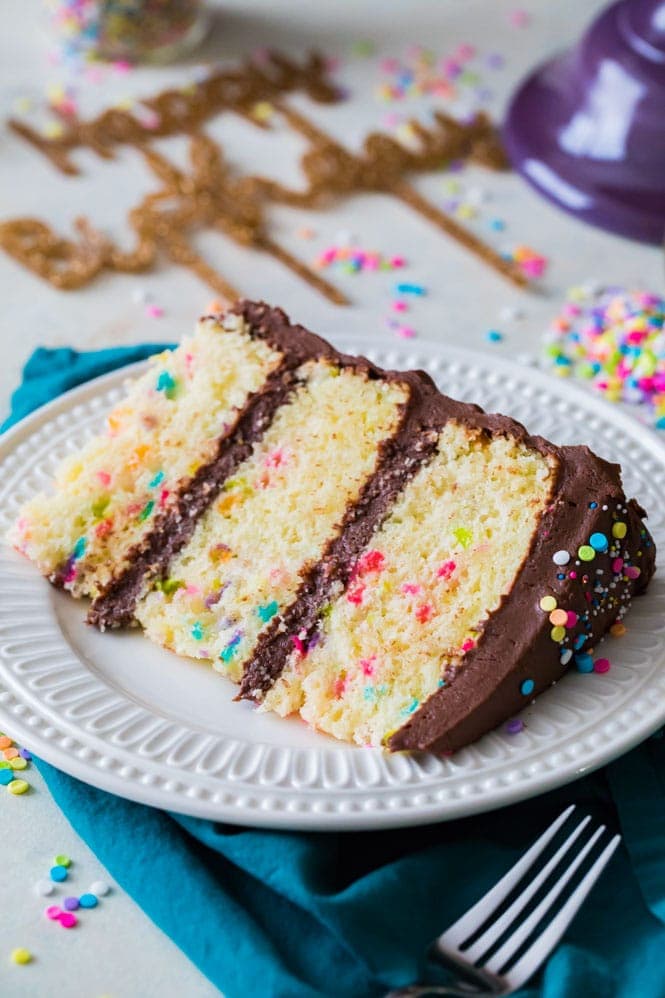 Slice of vanilla birthday cake on white plate