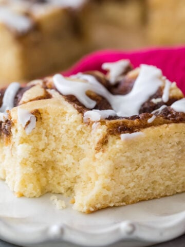 square slice of iced cinnamon roll cake that's missing one bite