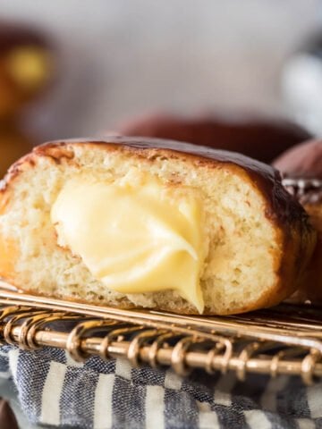 A ganache topped Boston cream donut that's been cut in half to show the pastry cream filling