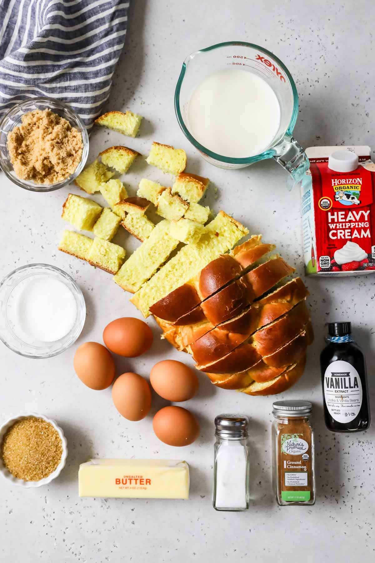 Overhead view of ingredients including challah bread, heavy cream, eggs, cinnamon, and more.