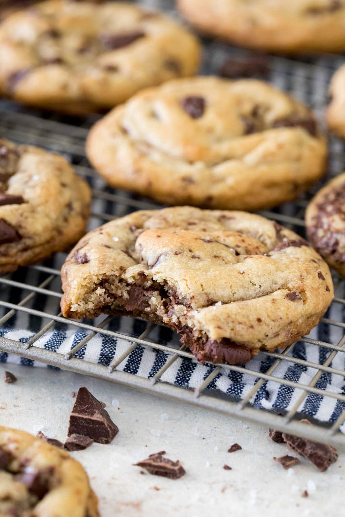 Chocolate chip cookie missing a bite on a metal cooling rack.