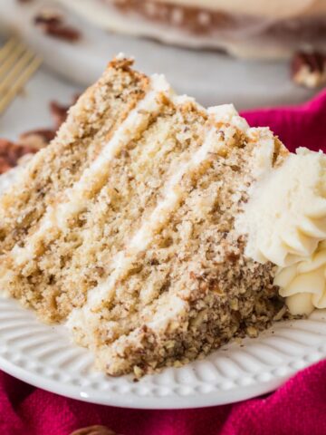 Slice of three layer butter pecan cake on a plate.
