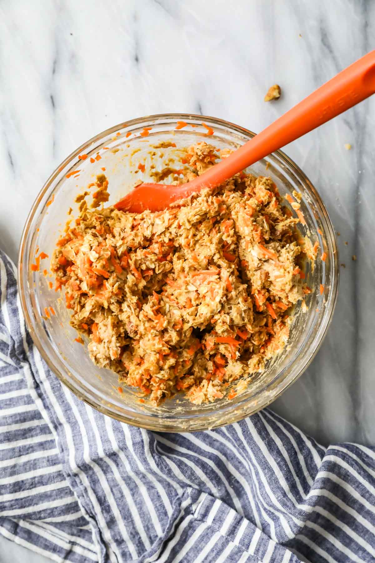 Overhead view of a bowl of cookie dough made with shredded carrots, oats, walnuts, and more.