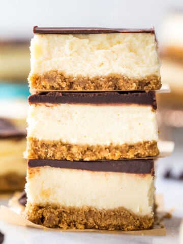 three ganache covered cheesecake bars stacked on top of each other