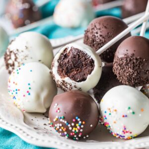 White and dark chocolate coated chocolate cake pops on a plate, with the middle pop missing a bite.