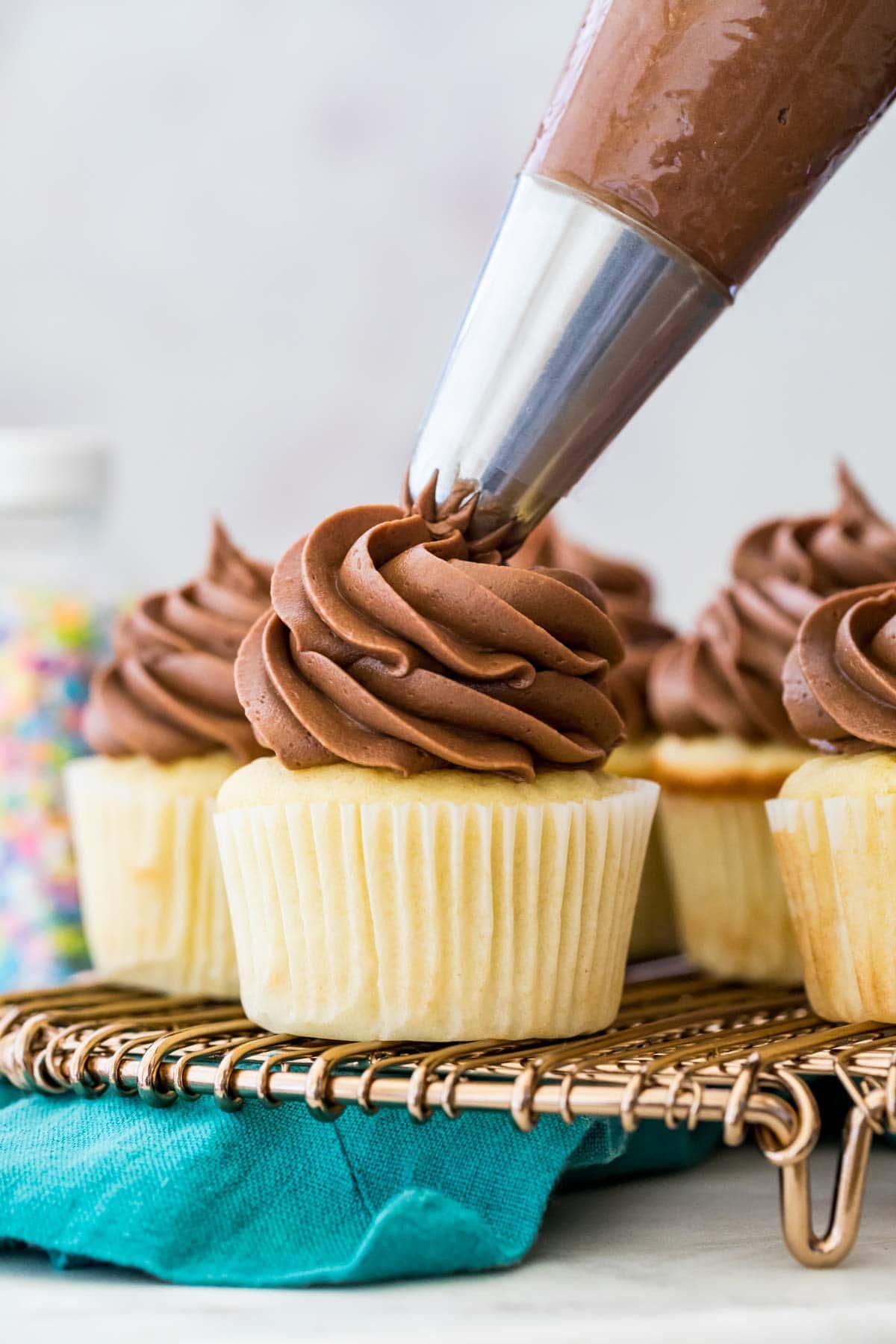 Piping chocolate frosting on a cupcake.