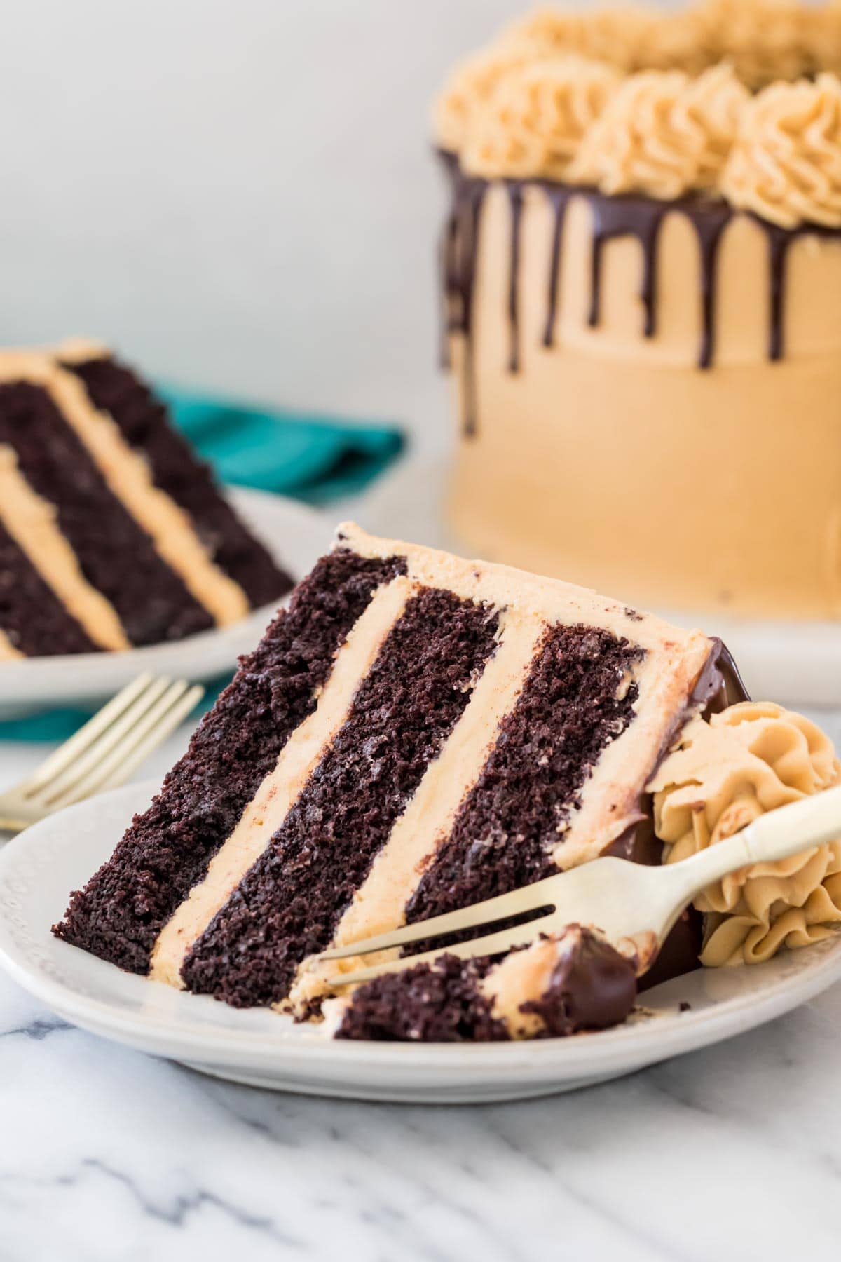 fork taking a bite of a three-layer peanut butter chocolate cake with peanut butter icing