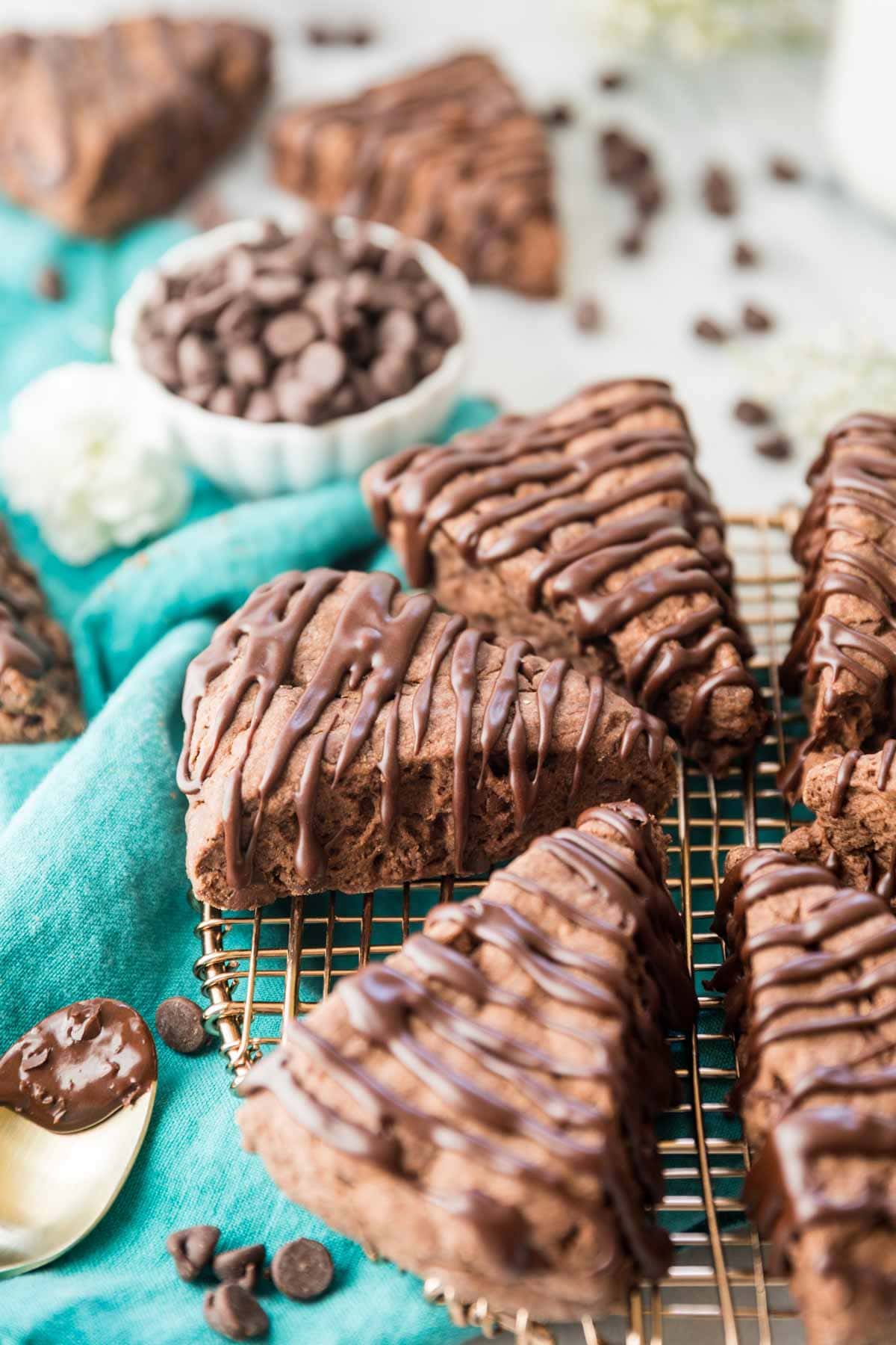 wedge-shaped chocolate scones drizzled with a chocolate glaze on a metal cooling rack