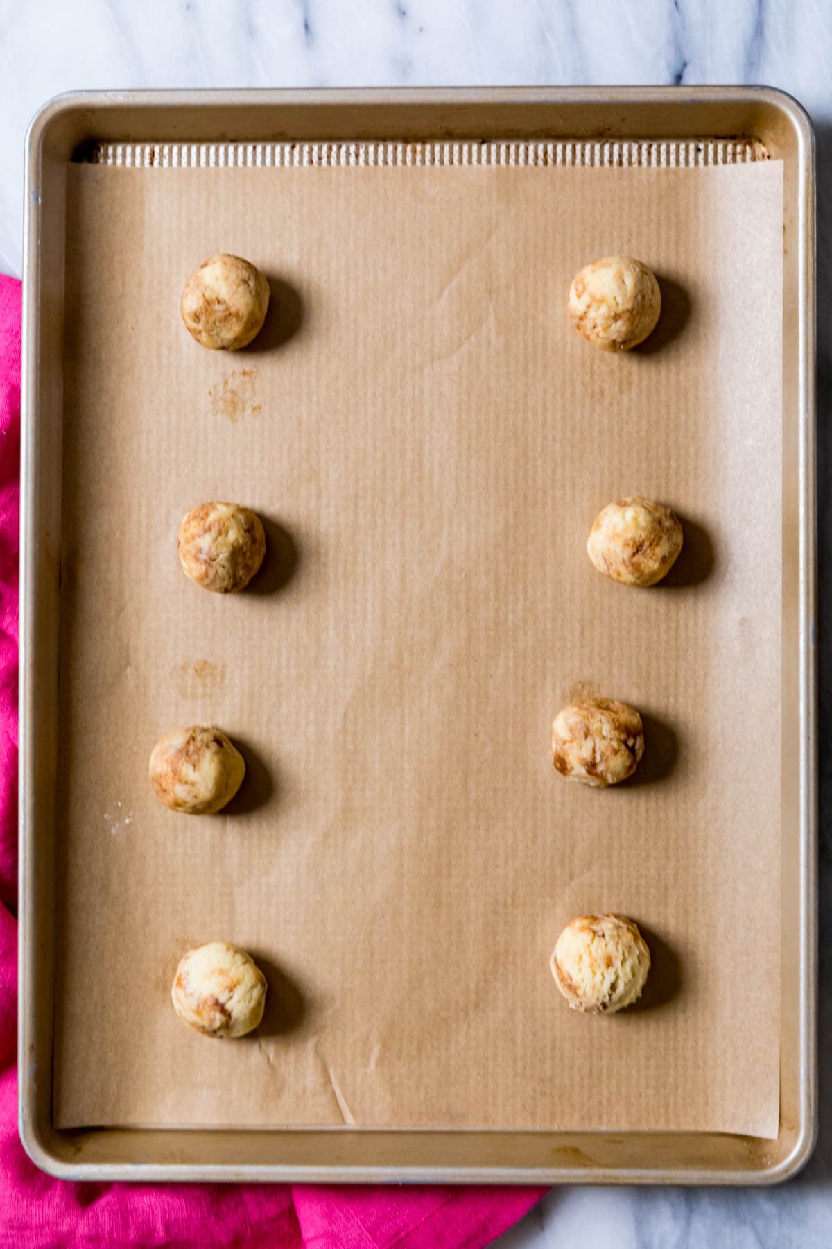 Overhead view of cinnamon cookie dough balls on a cookie sheet.