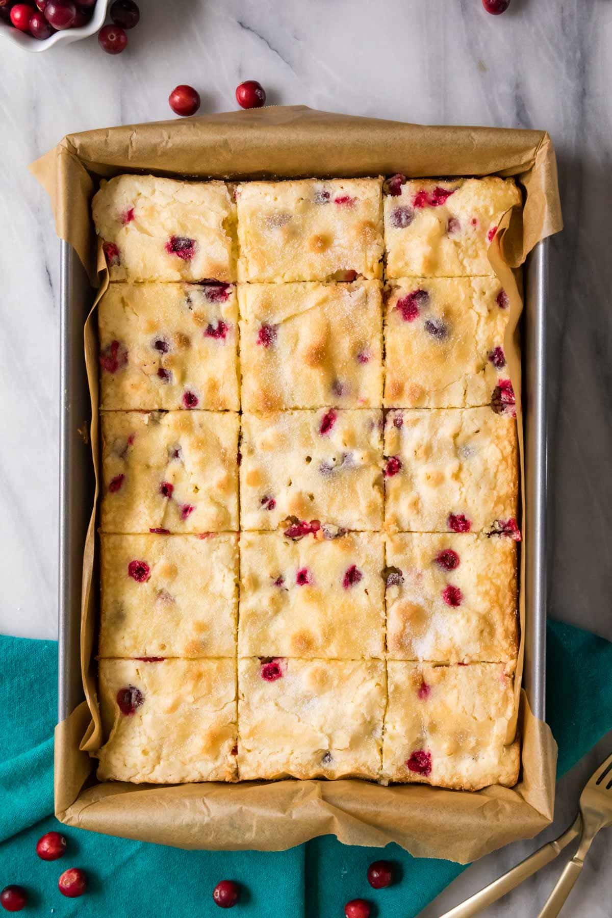 Overhead view of a cake made with fresh cranberries cut into squares while still in its pan.