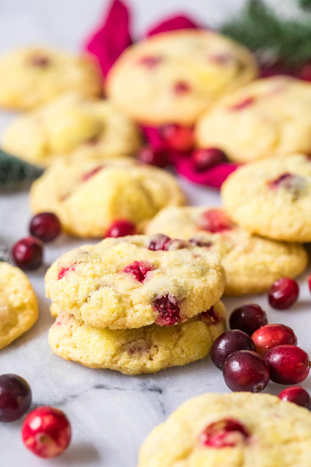 Two orange cranberry cookies stacked on top of each other with more cookies in the background.