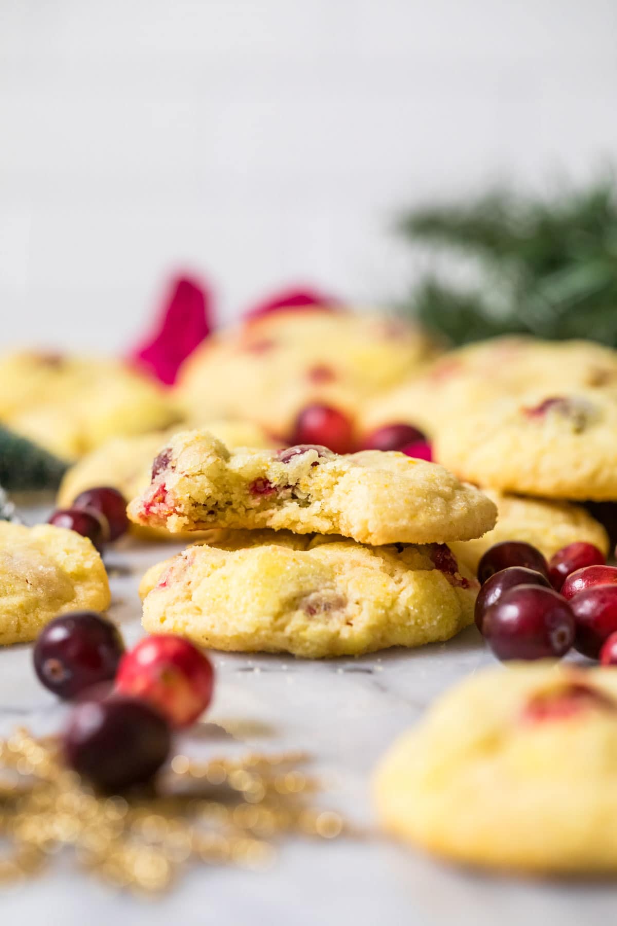 Two orange cranberry cookies stacked on top of each other with the top cookie missing a bite.