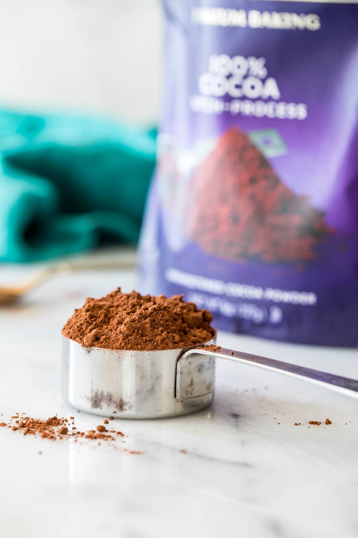 measuring cup of dutch processed cocoa powder sitting in front of a bag of cocoa