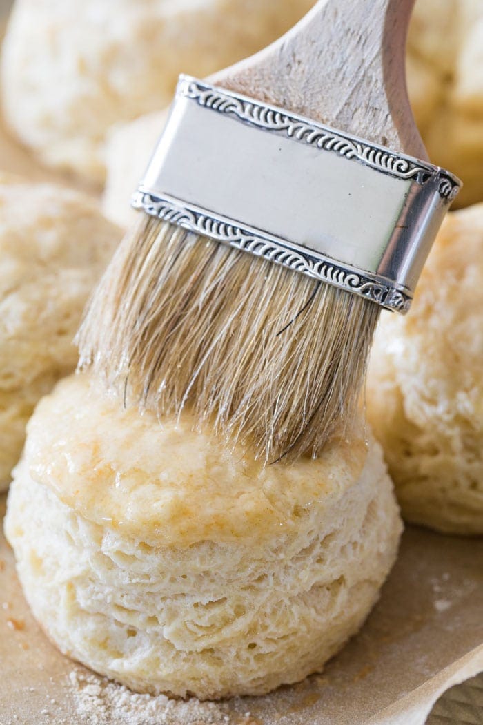 Brushing melted butter on a freshly baked homemade biscuit