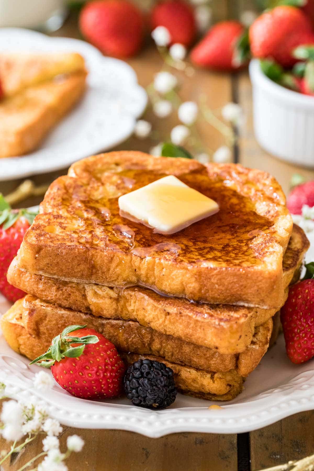 Three slices of french toast with a pat of butter and maple syrup on top.