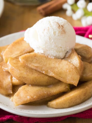 Fried apples topped with ice cream on white plate