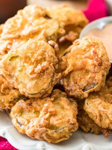 Homemade fried pickles stacked around a dipping sauce.