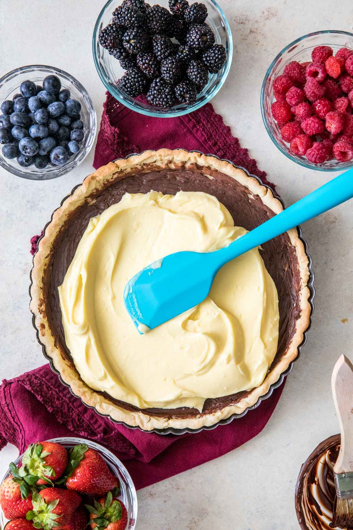 Spreading pastry cream over chocolate brushed tart crust