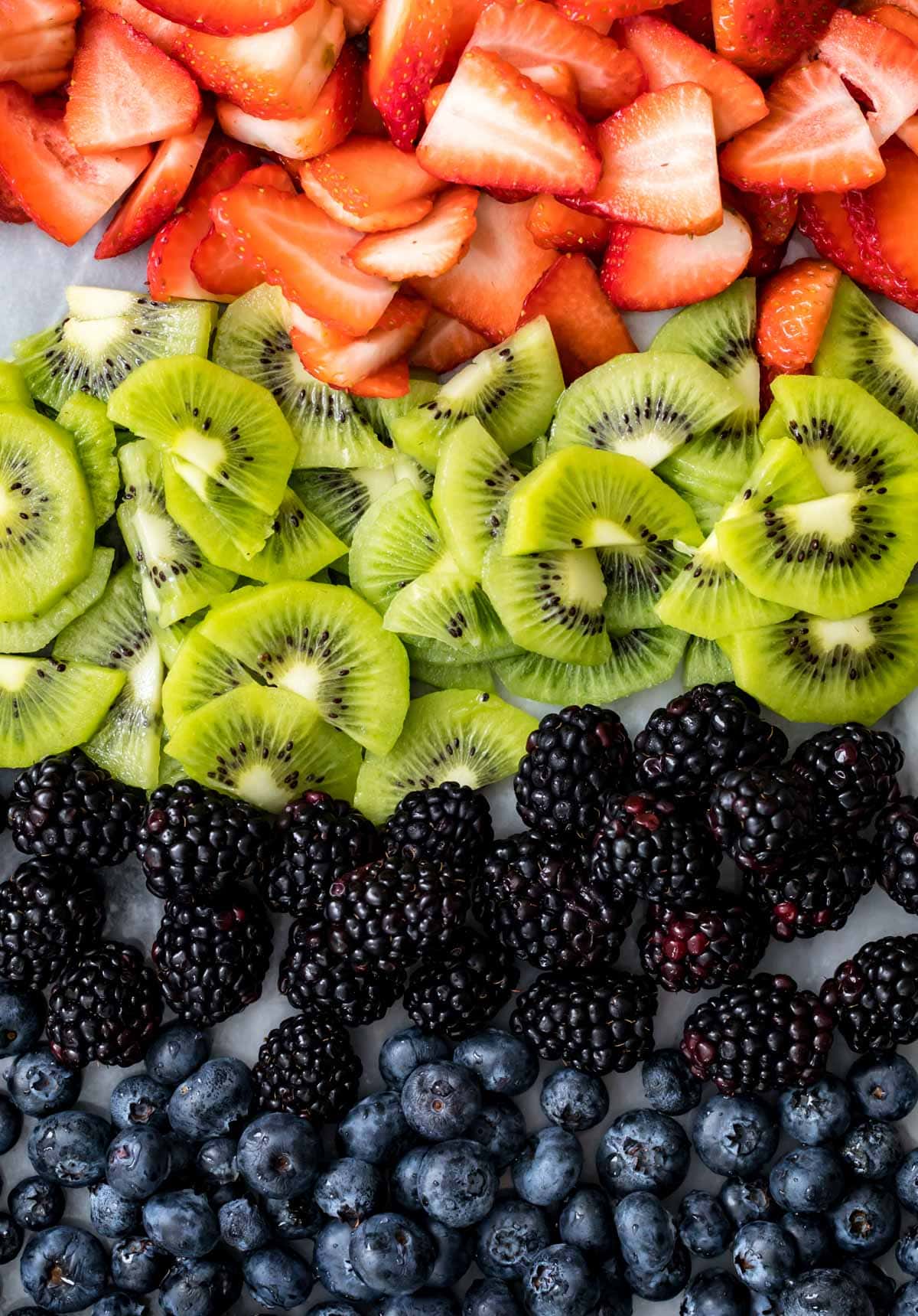 Array of fruit: strawberry and kiwi slices, blackberries and blueberries