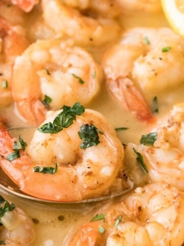 garlic butter shrimp being spooned out of a saucepan