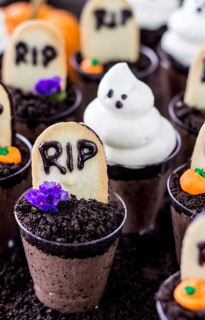 Ghosts in the graveyard dessert shooters, topped with mini tombstones, mini pumpkins, and ghoulish figures