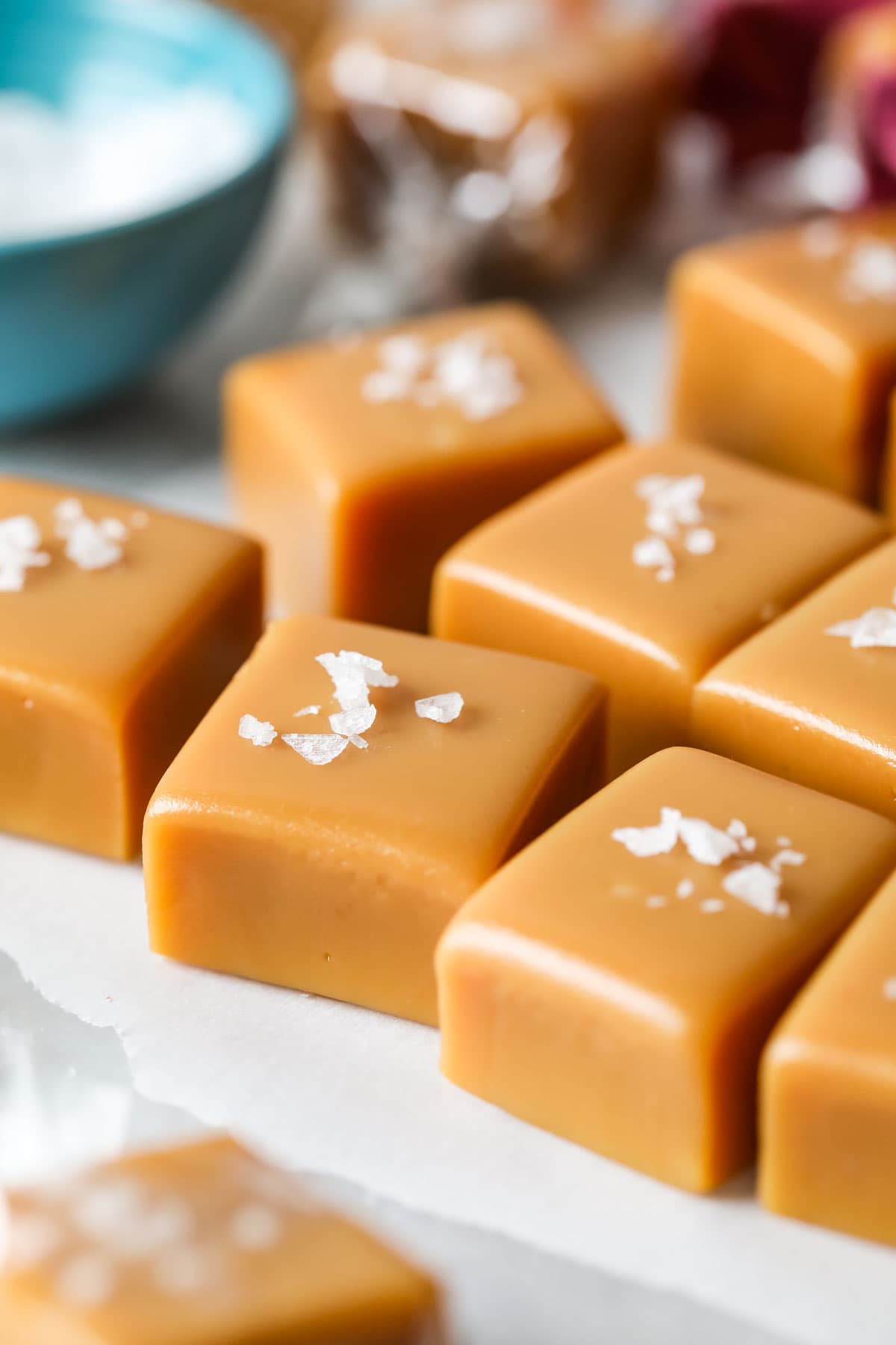 Close up view of squares of homemade caramel topped with flaky sea salt.