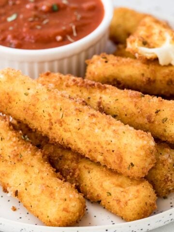 Homemade mozzarella sticks and marinara sauce on plate.