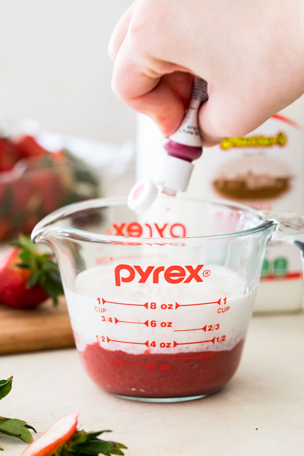 combining milk, strawberry puree, and food coloring in measuring cup