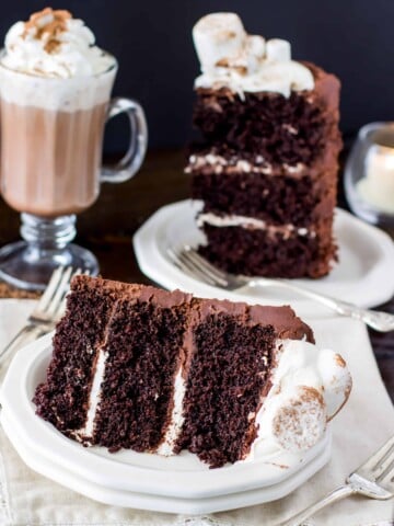 Slice of hot chocolate cake topped with marshmallows with a mug of hot chocolate in the background