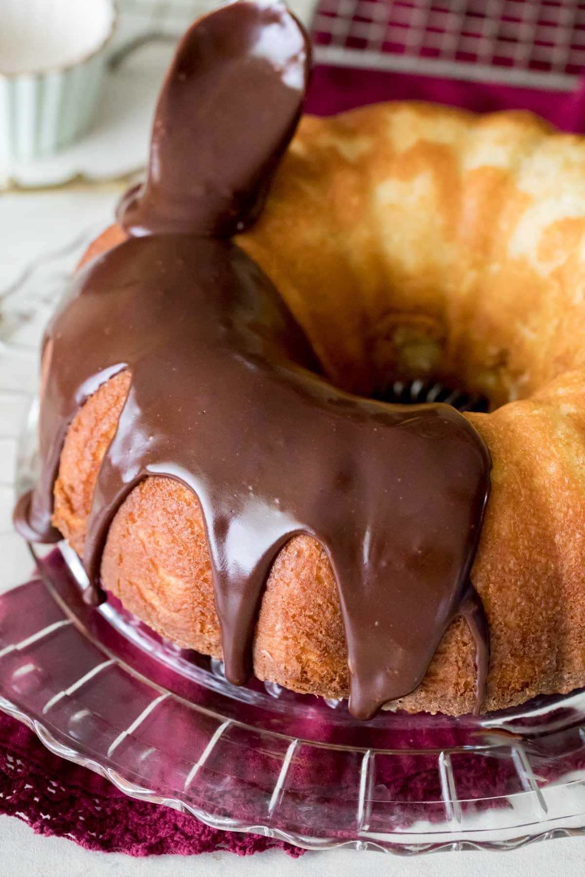 chocolate fudge frosting being poured onto a golden brown bundt cake
