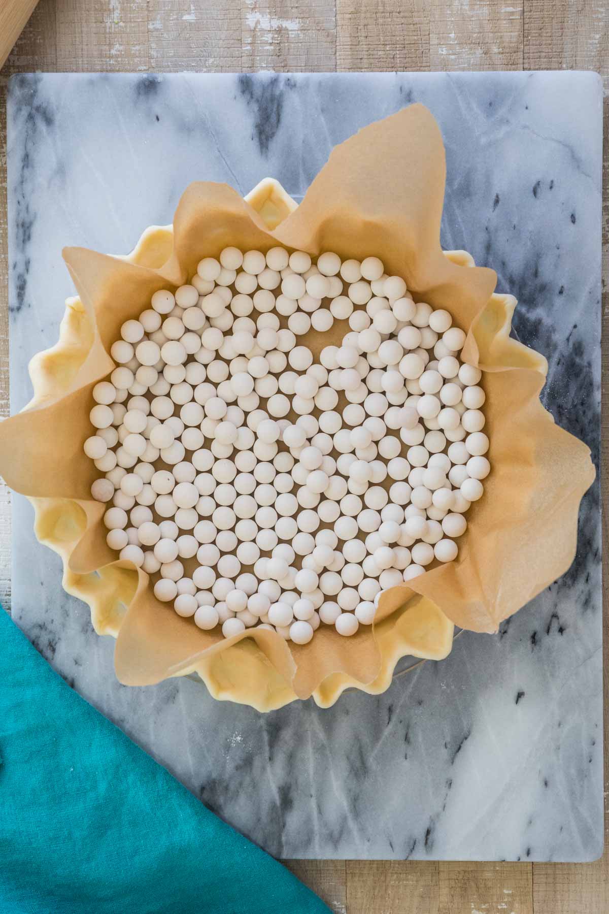 overhead view of unbaked pie crust lined with parchment paper and pie weights