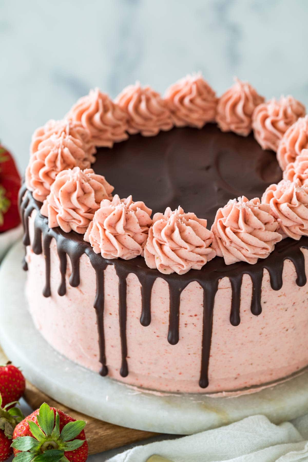 Cake decorated with pink strawberry icing, a chocolate ganache drip, and pink icing swirls.
