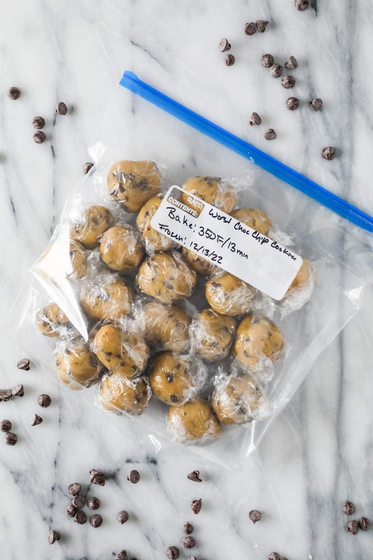 Ziploc bag of cookie dough balls that have been wrapped in plastic in preparation for freezing.