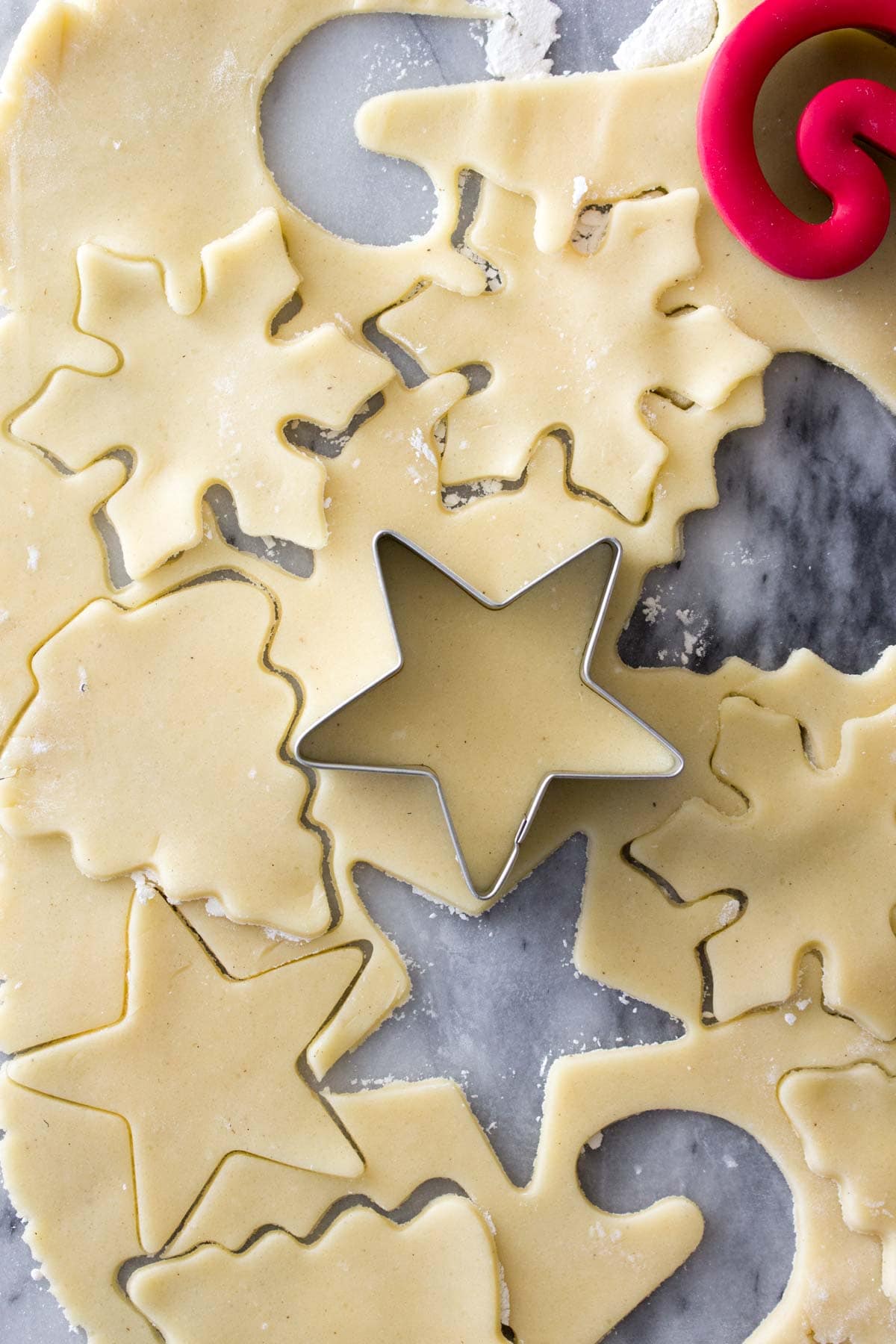 Sugar cookie recipe dough being cut into festive shapes with cookie cutter