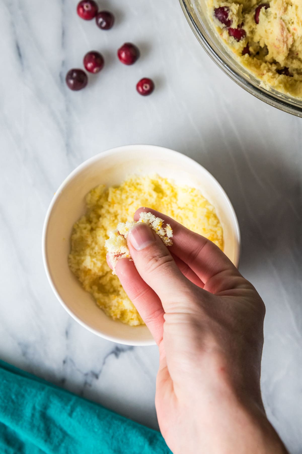 Overhead view of hands rubbing orange zest and sugar together to make orange sugar.