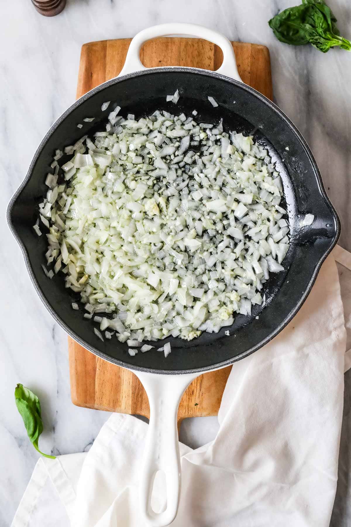 Overhead view of onion and garlic cooking in a cast iron pan.