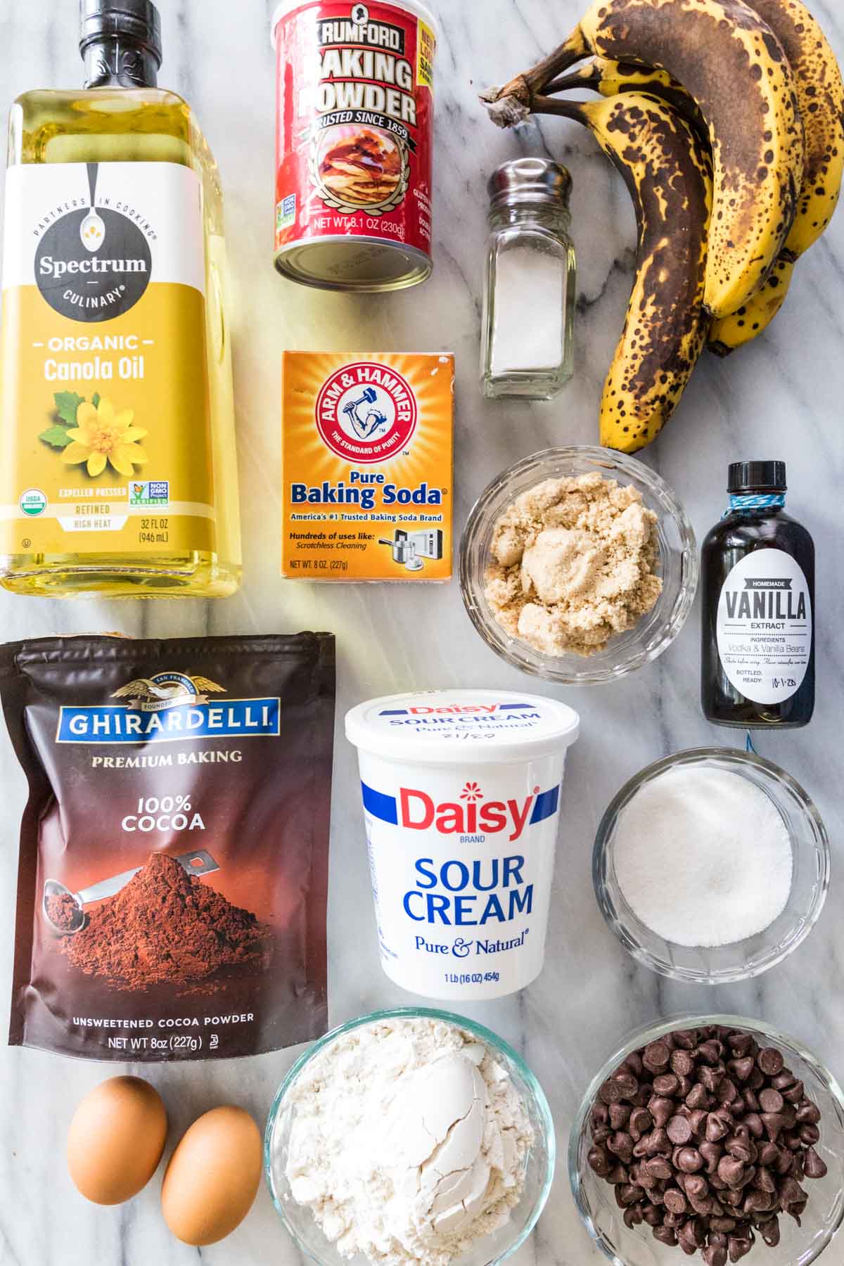 overhead view of ingredients including ripe bananas, oil, sour cream, cocoa powder, and more