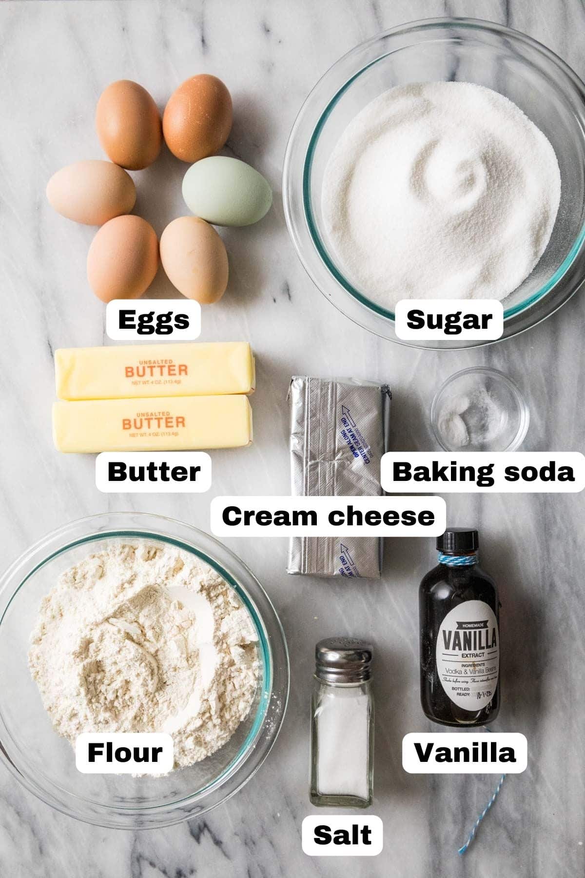 Overhead view of labelled ingredients including eggs, sugar, cream cheese, butter, and more.