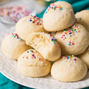 Pile of Italian cookies on a plate with one cookie missing a bite.