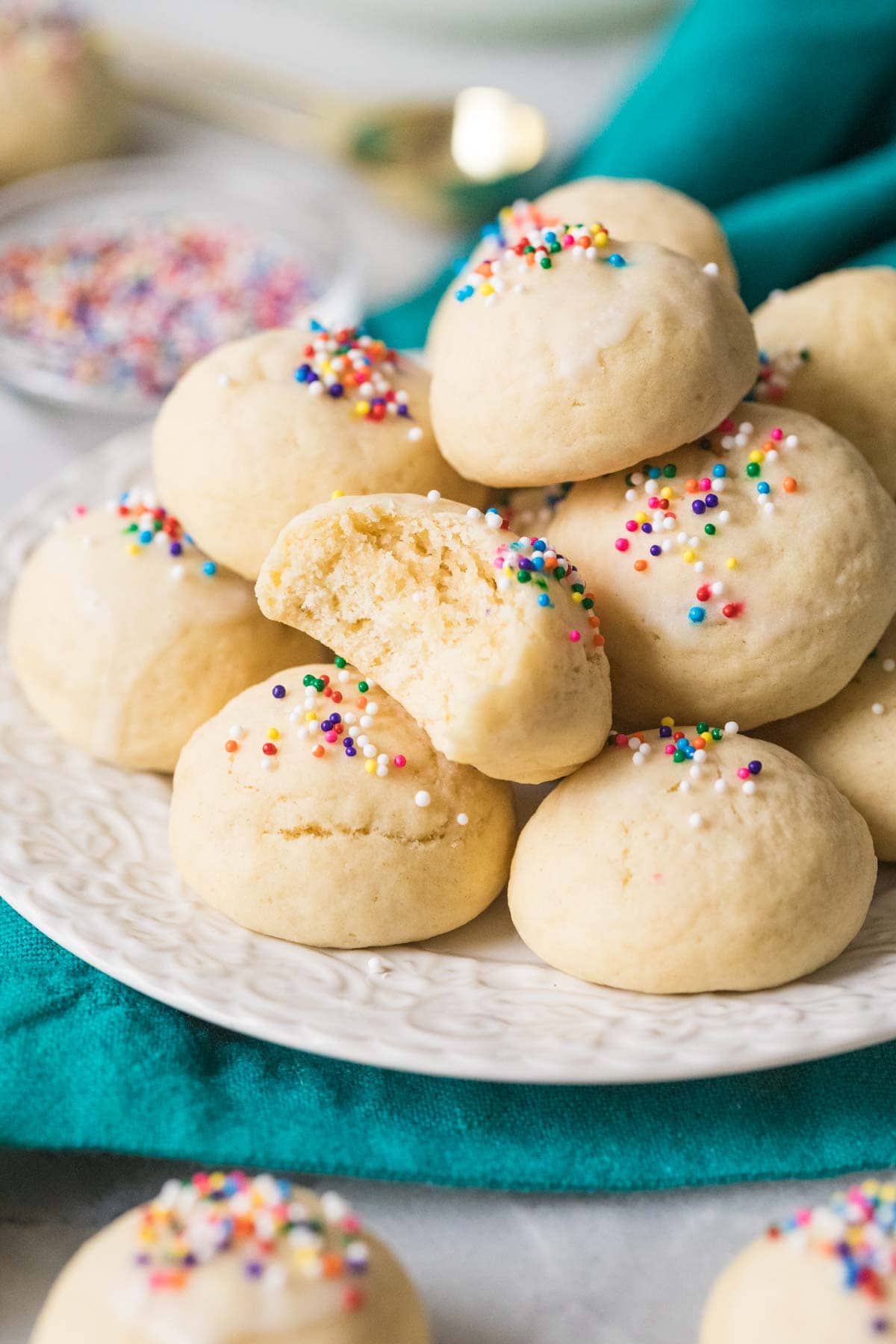 Pile of Italian cookies on a plate with one cookie missing a bite.