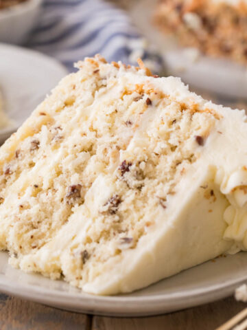 slice of italian cream cake consisting of three layers of cake studded with coconut and pecans frosted with a cream cheese frosting