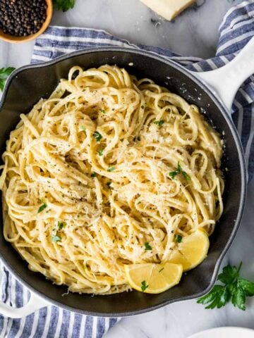 Overhead view of a skillet filled with lemon pasta and fresh lemon slices.